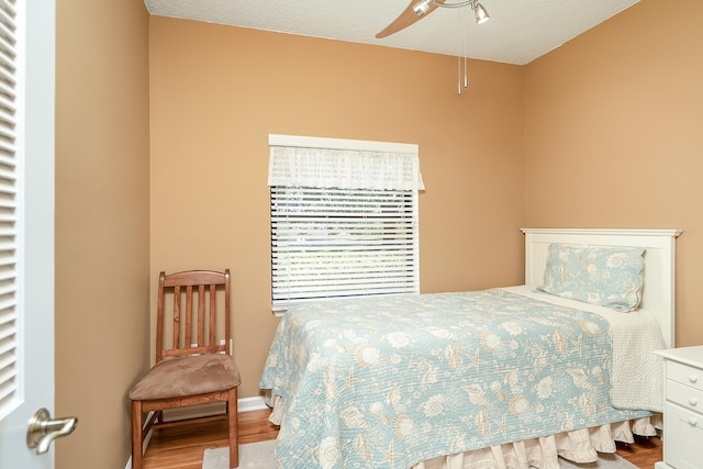 bedroom with hardwood / wood-style floors, ceiling fan, and a textured ceiling