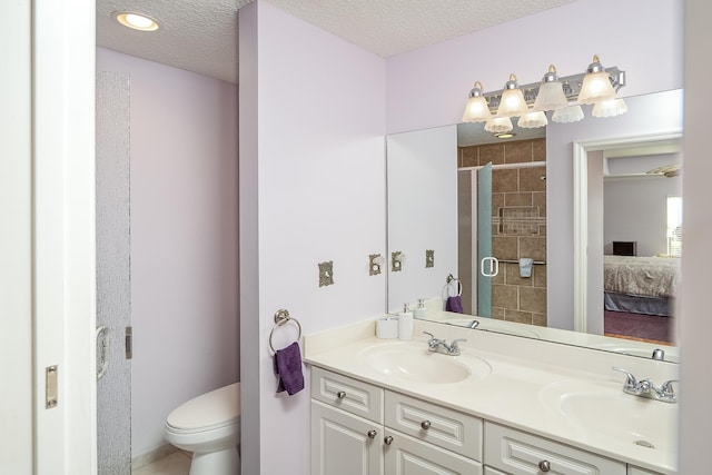 bathroom featuring a textured ceiling, vanity, toilet, and a shower with door