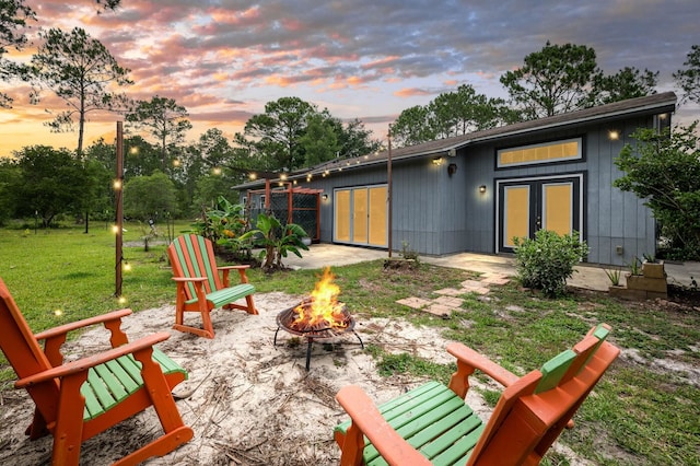4405 Alvin St, Hastings, FL 32145 - back of house at dusk with an outdoor fire pit, a lawn, and a patio