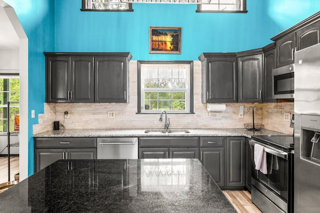 4405 Alvin St, Hastings, FL 32145 - kitchen featuring stainless steel appliances, a sink, decorative backsplash, dark stone countertops, and light wood-style flooring