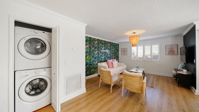 108 A St Unit A, Saint Augustine, FL 32080 - laundry room featuring stacked washer / drying machine, crown molding, a textured ceiling, and light wood-type flooring