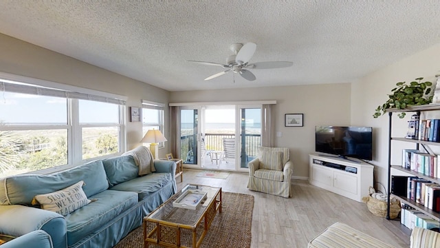 living room featuring light wood-style floors, a textured ceiling, and a ceiling fan