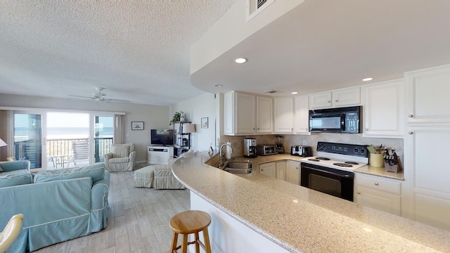 kitchen with black microwave, range with electric stovetop, open floor plan, and a sink