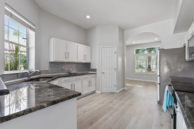 unfurnished living room with a tiled fireplace, ceiling fan, built in features, and light wood-type flooring