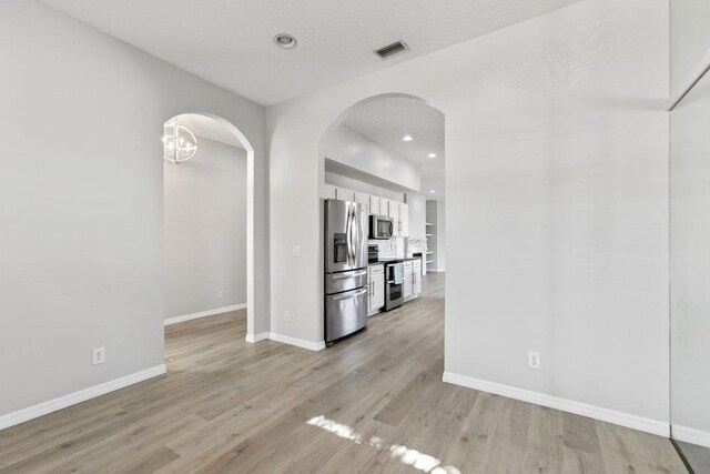 kitchen with stainless steel appliances, white cabinets, backsplash, and light hardwood / wood-style flooring