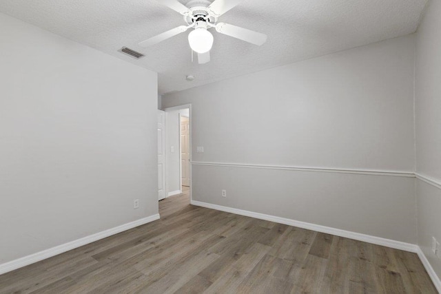 empty room with wood-type flooring, ceiling fan, and a textured ceiling