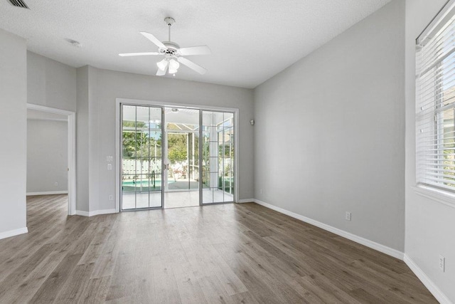 empty room featuring a textured ceiling, wood-type flooring, and ceiling fan