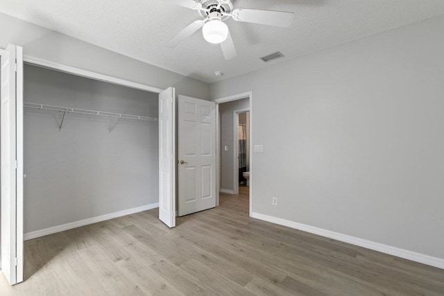 unfurnished bedroom featuring ceiling fan, a closet, light hardwood / wood-style flooring, and a textured ceiling