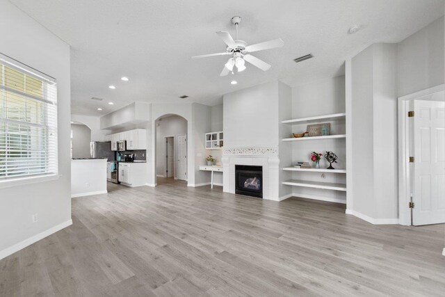 empty room with ceiling fan, a tray ceiling, and light wood-type flooring