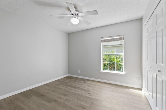 unfurnished bedroom featuring ceiling fan, a textured ceiling, a closet, and light hardwood / wood-style flooring