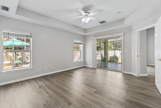 unfurnished room with ceiling fan, dark hardwood / wood-style floors, and a raised ceiling