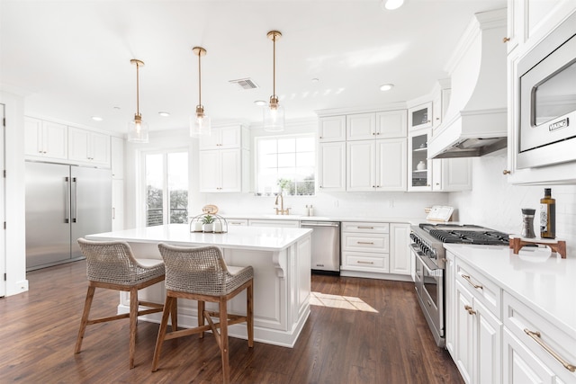 211 2nd St, Saint Augustine, FL 32080 - kitchen with built in appliances, recessed lighting, white cabinets, premium range hood, and a breakfast bar area