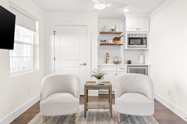 living area with sink, dark wood-type flooring, and ornamental molding