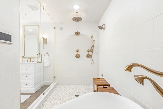 bathroom featuring shower with separate bathtub, vanity, and tile walls