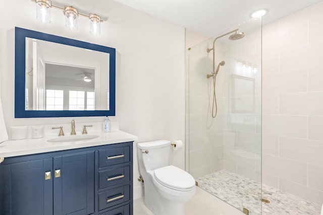 bathroom with tiled shower, vanity, and toilet