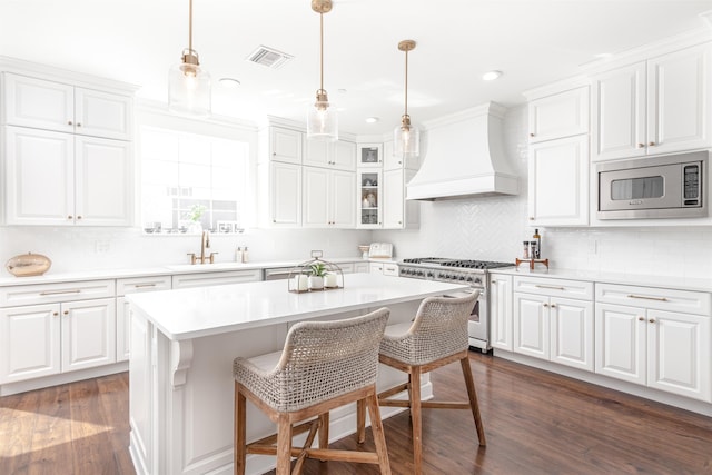 kitchen with appliances with stainless steel finishes, a center island, premium range hood, and white cabinetry