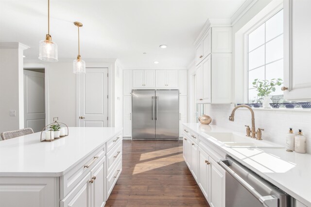 kitchen featuring sink, a kitchen island, pendant lighting, white cabinets, and appliances with stainless steel finishes