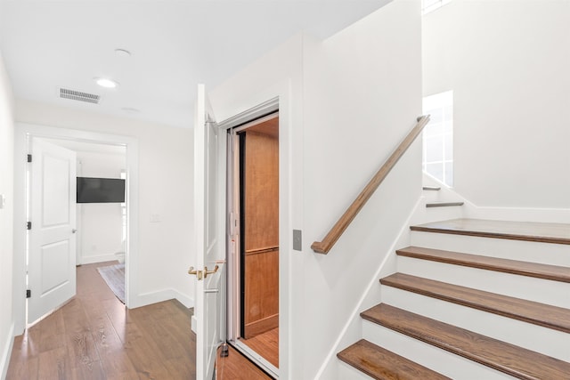 stairs featuring hardwood / wood-style floors