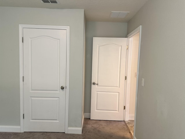 hall featuring dark colored carpet