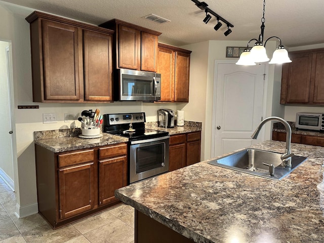 kitchen with light tile patterned flooring, sink, hanging light fixtures, a textured ceiling, and appliances with stainless steel finishes