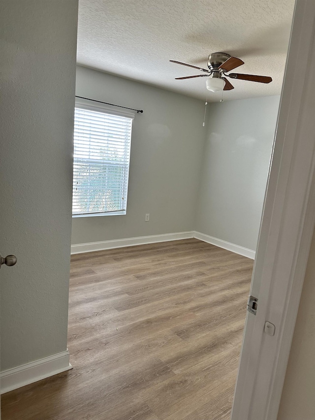 unfurnished room with ceiling fan, a textured ceiling, and light wood-type flooring