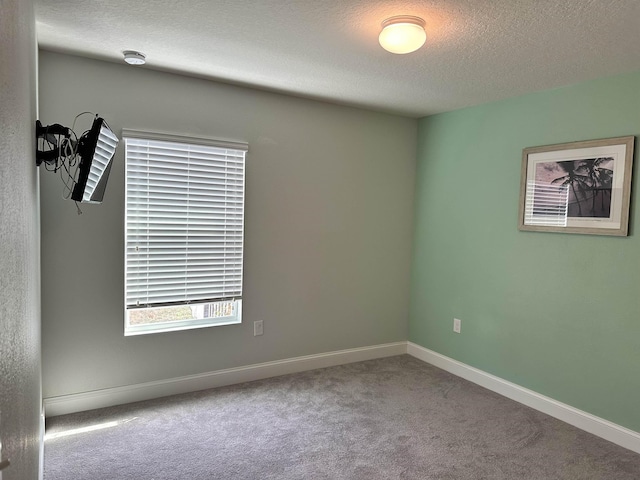 carpeted empty room with a textured ceiling