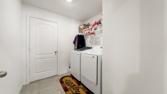 laundry area featuring light tile patterned floors, a textured ceiling, and separate washer and dryer