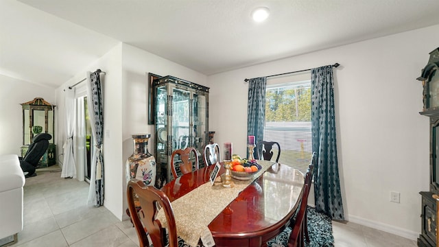 tiled dining space featuring lofted ceiling