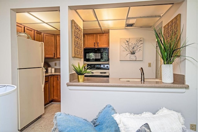 kitchen featuring white fridge, sink, and range with electric cooktop