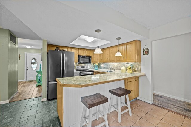 kitchen with a kitchen breakfast bar, sink, hanging light fixtures, appliances with stainless steel finishes, and kitchen peninsula