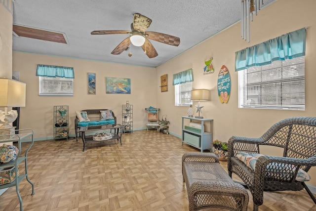 sitting room with ceiling fan, plenty of natural light, light parquet floors, and a textured ceiling