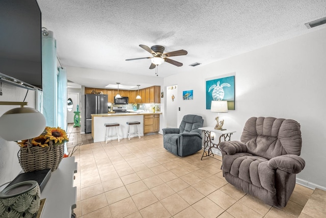 living room with ceiling fan, light tile patterned floors, and a textured ceiling