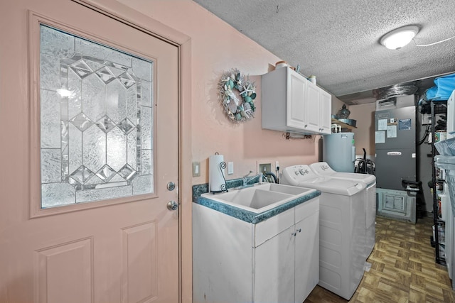 laundry room with cabinets, dark parquet flooring, electric water heater, sink, and a textured ceiling