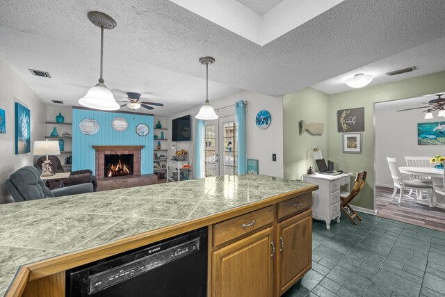 kitchen with dishwasher, wooden walls, ceiling fan, a textured ceiling, and decorative light fixtures