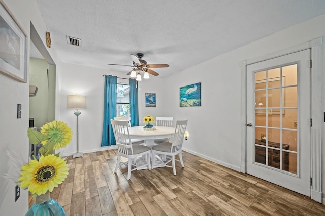 dining space with hardwood / wood-style flooring, ceiling fan, and a textured ceiling