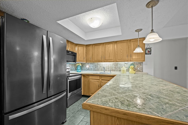 kitchen with kitchen peninsula, appliances with stainless steel finishes, decorative backsplash, a raised ceiling, and sink