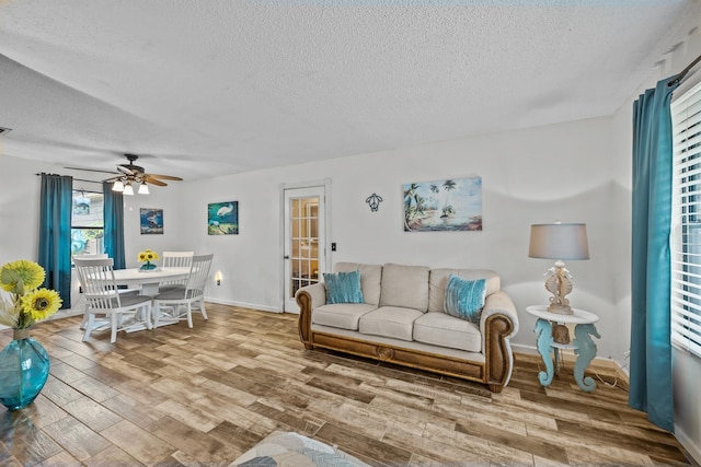 living room featuring ceiling fan, wood-type flooring, and a textured ceiling