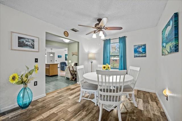 dining area featuring hardwood / wood-style flooring, ceiling fan, and a textured ceiling