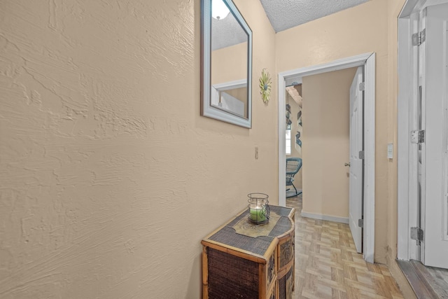 corridor with light parquet flooring and a textured ceiling