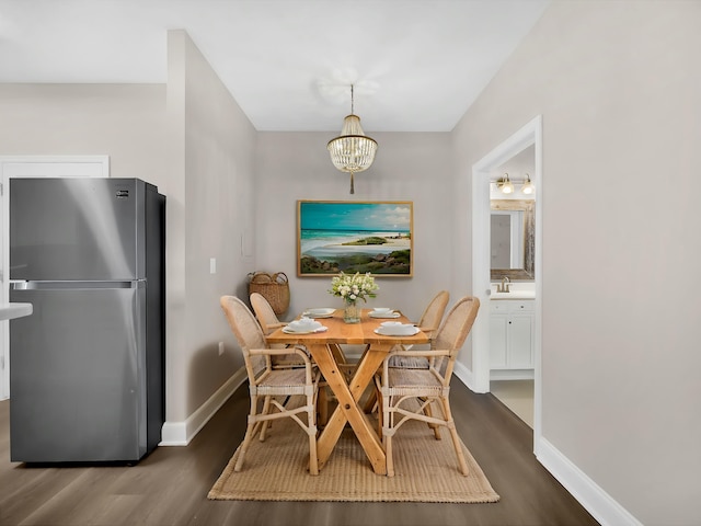dining space with dark wood-type flooring, baseboards, and a notable chandelier