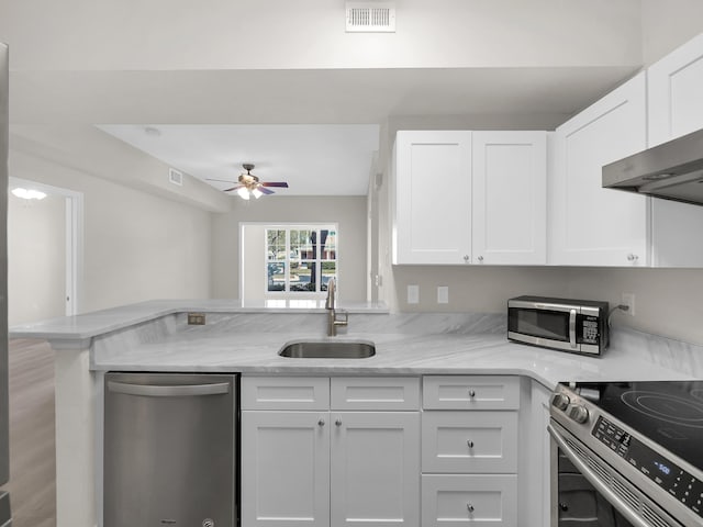 kitchen with a ceiling fan, a peninsula, a sink, white cabinets, and appliances with stainless steel finishes