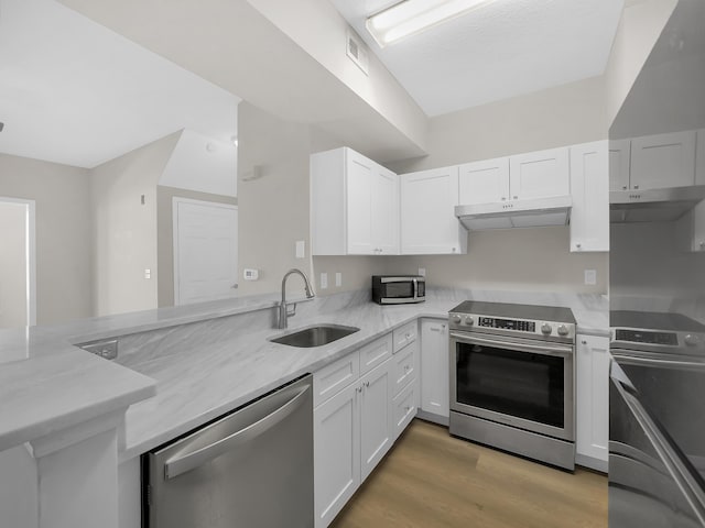 kitchen with under cabinet range hood, a sink, stainless steel appliances, white cabinets, and light stone countertops