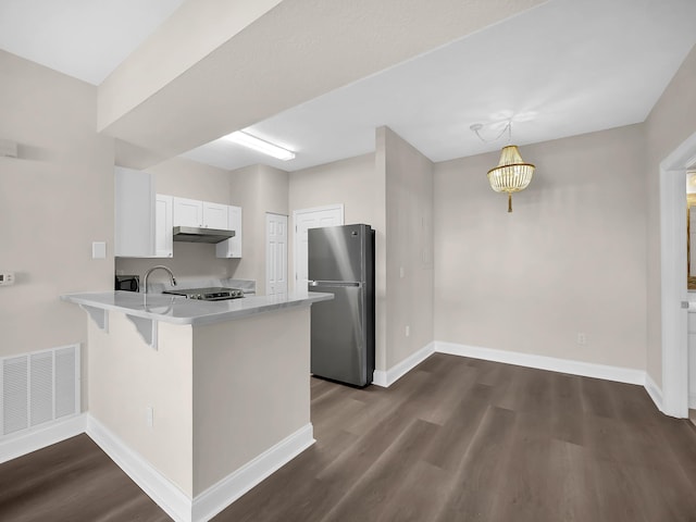 kitchen featuring visible vents, freestanding refrigerator, a peninsula, dark wood-type flooring, and light countertops