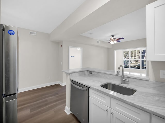 kitchen featuring visible vents, light stone counters, white cabinets, stainless steel appliances, and a sink