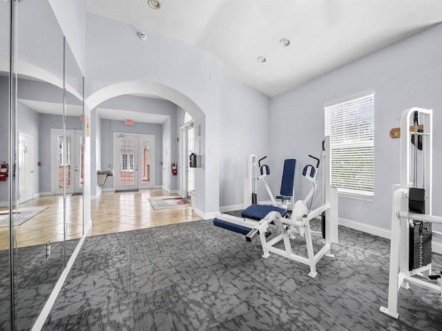 workout room with arched walkways, baseboards, recessed lighting, and light tile patterned flooring