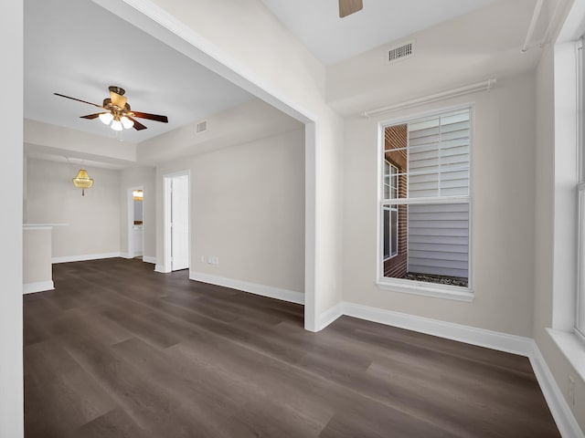 spare room featuring visible vents, baseboards, dark wood-type flooring, and a ceiling fan