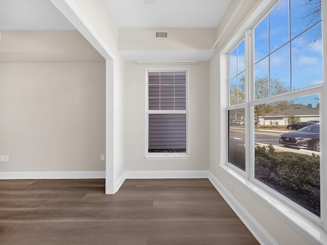 spare room featuring dark wood-style floors, visible vents, and baseboards