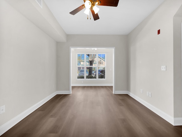 spare room with a ceiling fan, baseboards, and dark wood-style flooring