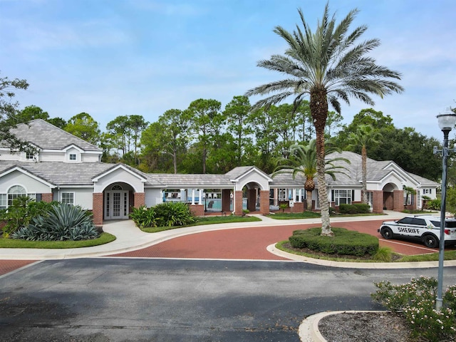 view of front of property featuring brick siding, french doors, and a tile roof