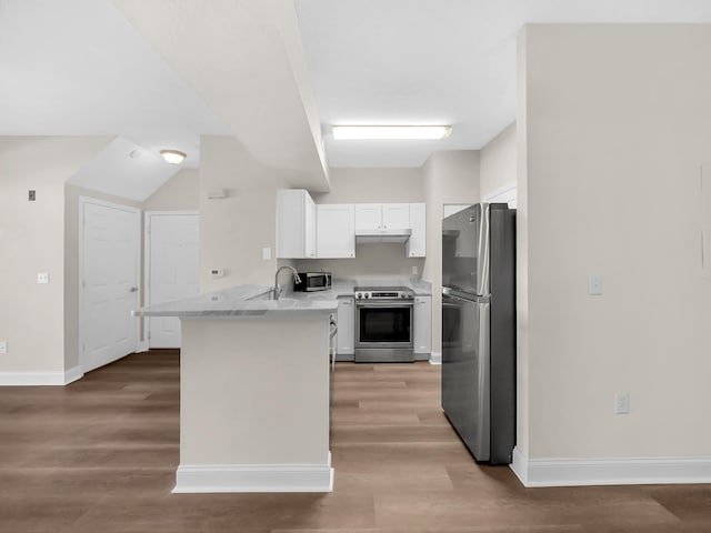 kitchen with wood finished floors, appliances with stainless steel finishes, a peninsula, white cabinets, and light countertops